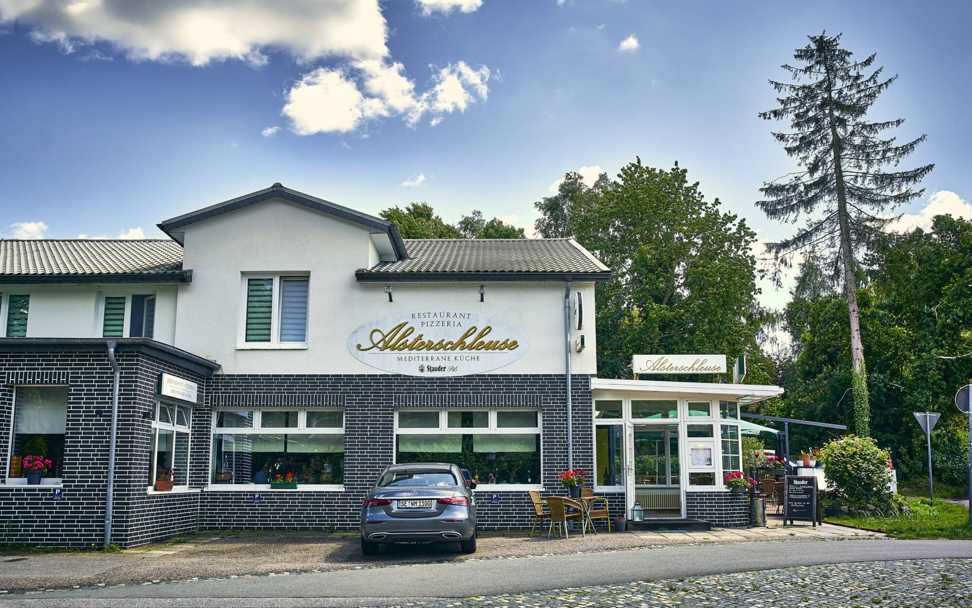 Ristorante Alsterschleuse in Tangstedt – Außenansicht des Restaurants an der Alsterschleuse mit Schild und Parkplätzen